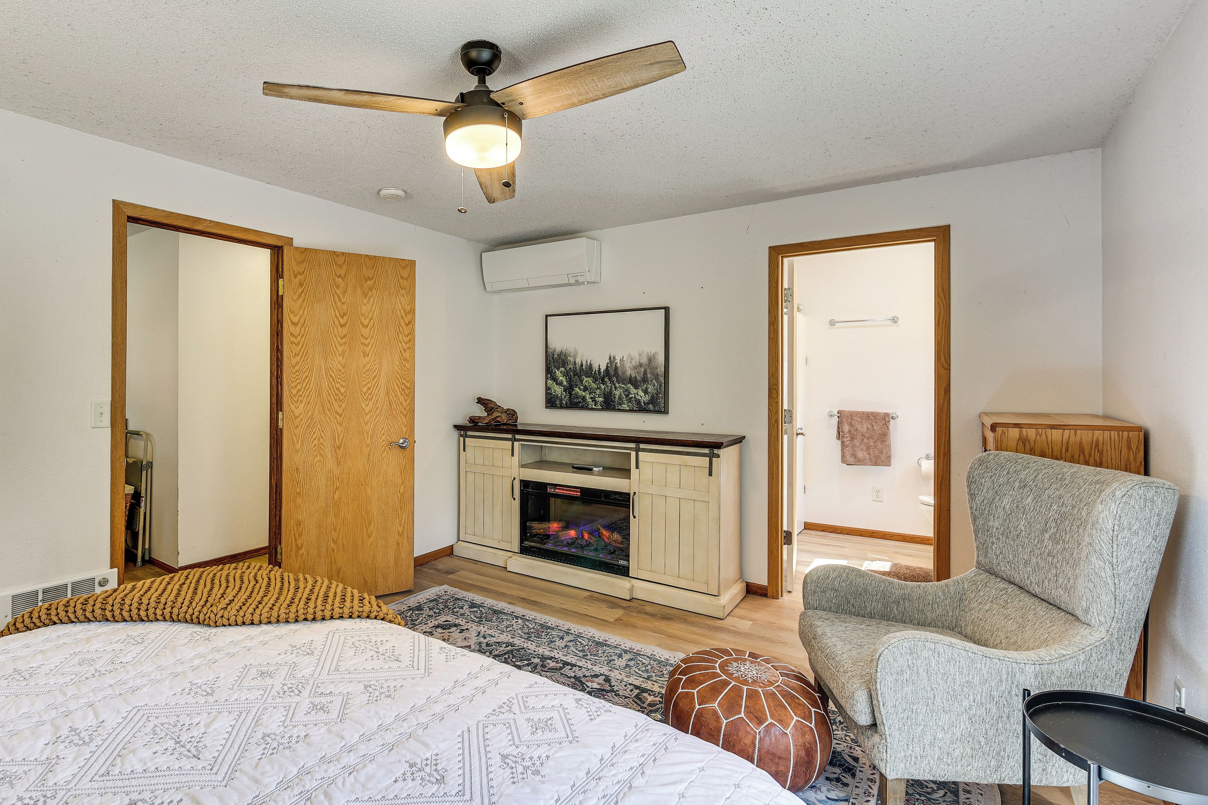 Une chambre à coucher avec un lit, une chaise, une cheminée et un ventilateur de plafond.