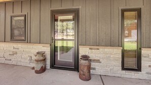 L’extérieur d’un bâtiment est caractérisé par un revêtement de couleur gris foncé, un socle en pierre et une porte à cadre noir dotée d’un panneau de verre.