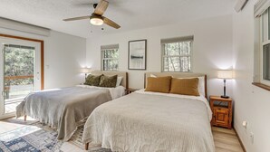 Une chambre avec deux lits, un ventilateur de plafond et une vue sur l’extérieur.