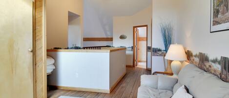 A cozy room with a wooden ceiling, a white sofa, a small table, and a painting on the wall.
