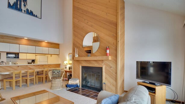 A modern living room with a fireplace, a television, and a dining area with wooden furniture.