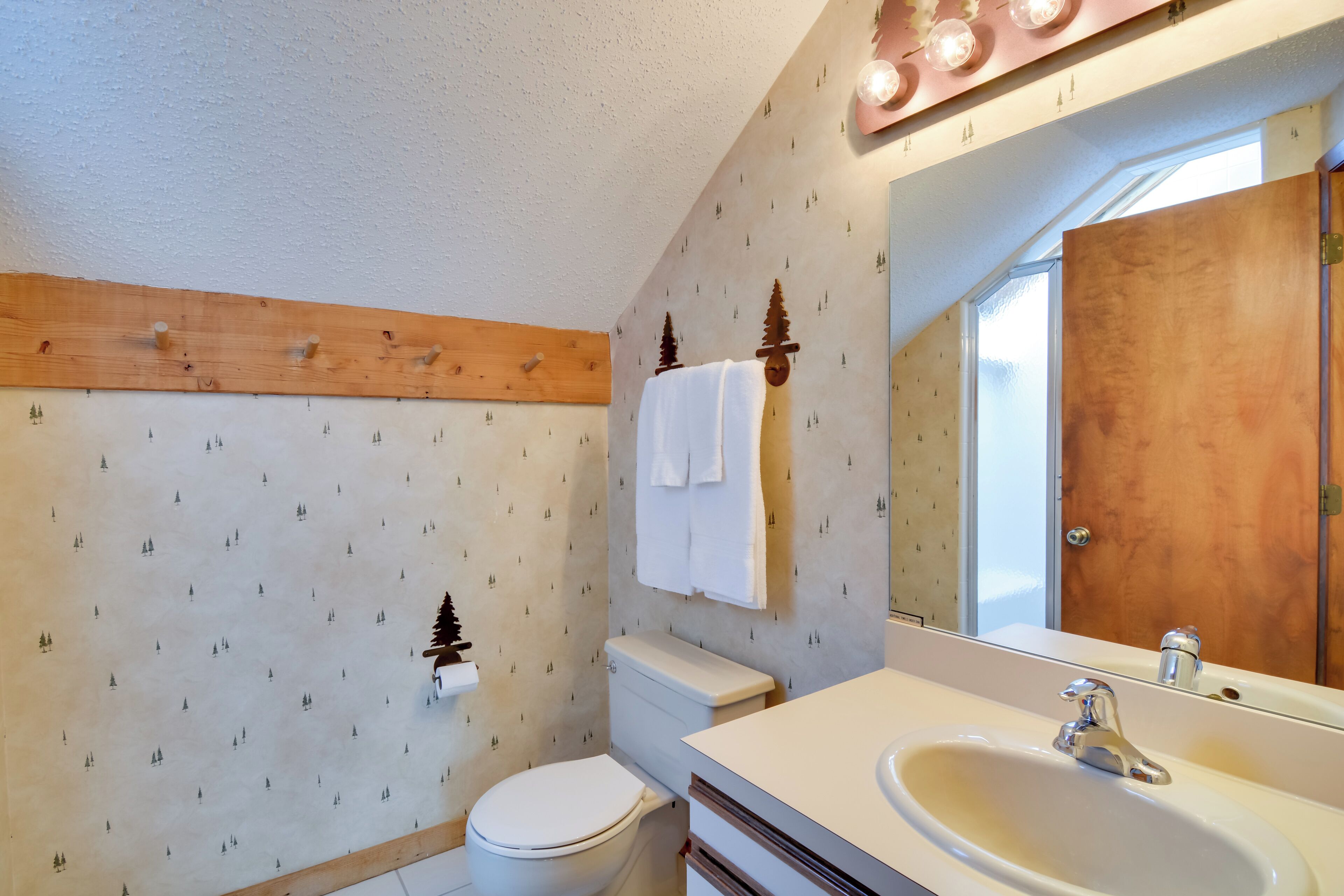 Une salle de bain avec un meuble-lavabo en bois, un lavabo blanc et des toilettes.