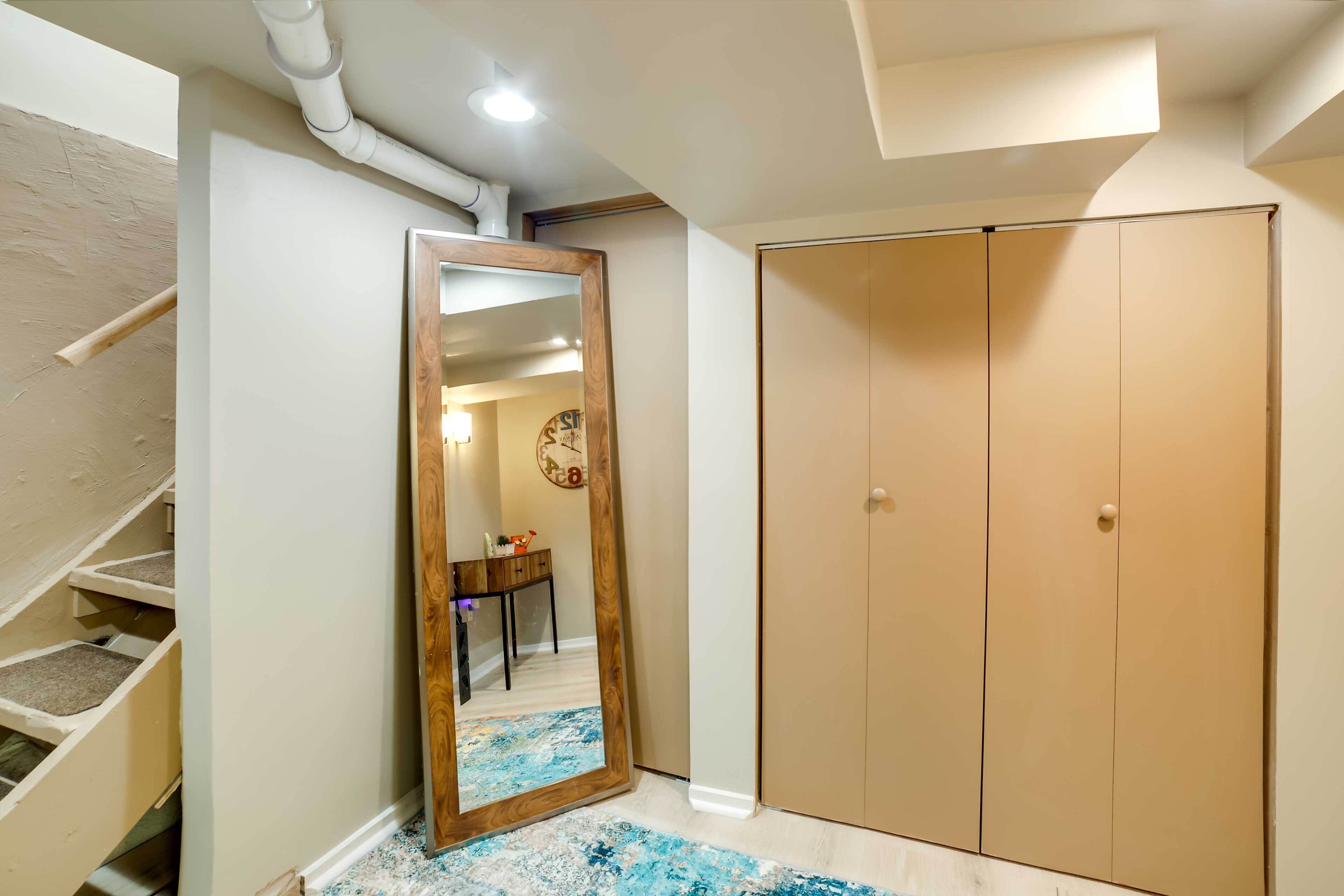 A hallway with a wooden-framed mirror, a wardrobe, and a staircase.