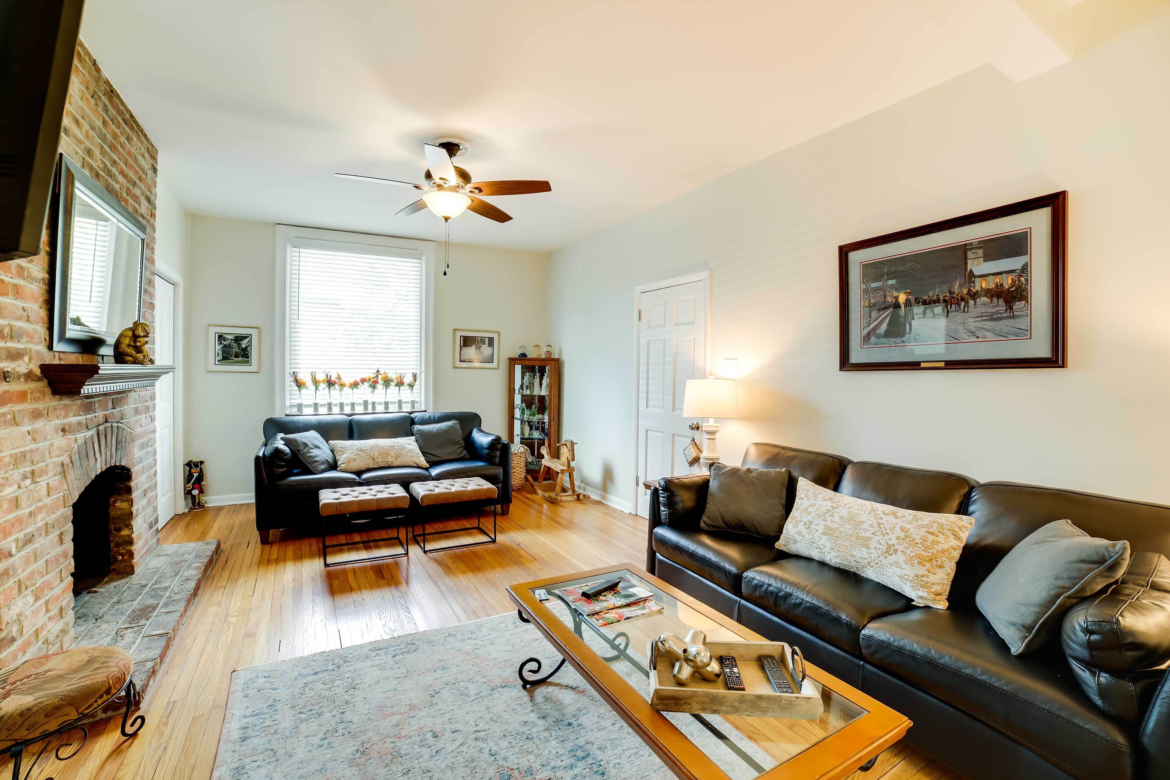 A living room with a fireplace, two sofas, a coffee table, and a ceiling fan.