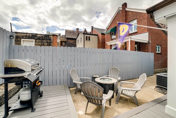 A patio area with a grill, outdoor seating, and a flag.