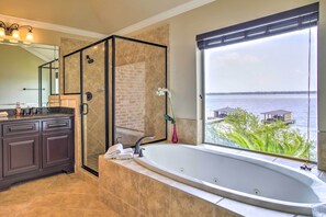 A modern bathroom with a large bathtub, a walk-in shower, and a view of the water. - Waterfront Home w/ Boat Dock on Lake Houston! (Houston)