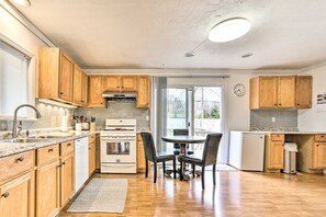 A kitchen with wooden cabinets, a stainless steel sink, a built-in oven, and a dining area with chairs and a table. - Ann Arbor Home: 3 Mi to Stadium & Yost Ice Arena (Ann Arbor)