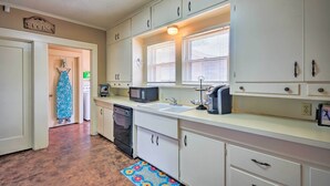 A kitchen with white cabinets, a microwave, a sink, and a dish rack. - Inviting Lubbock Home > 1 Mi to Downtown (Lubbock)