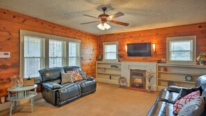 A cozy living room with a fireplace, leather sofas, and a ceiling fan. - Inviting Lubbock Home > 1 Mi to Downtown (Lubbock)