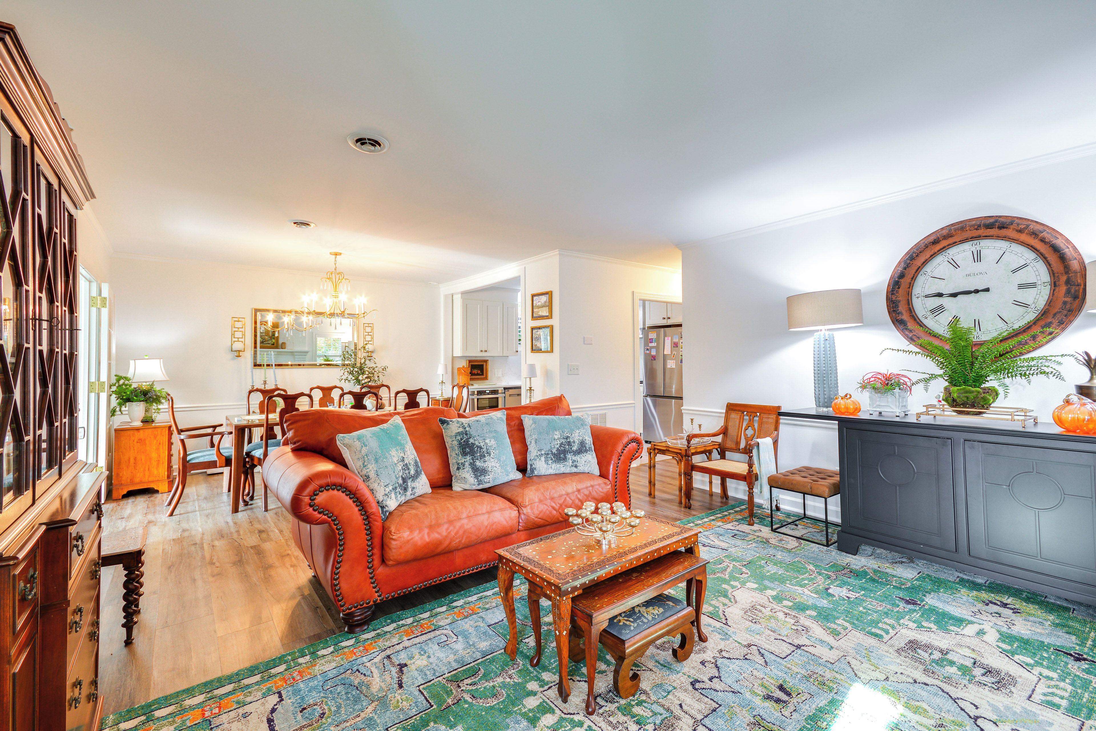 A spacious living room with a red leather sofa, wooden coffee table, and patterned rug.