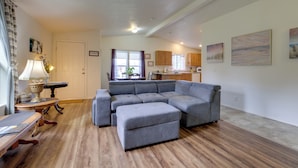 A modern living room with a sectional sofa, ottoman, and a dining table with chairs.