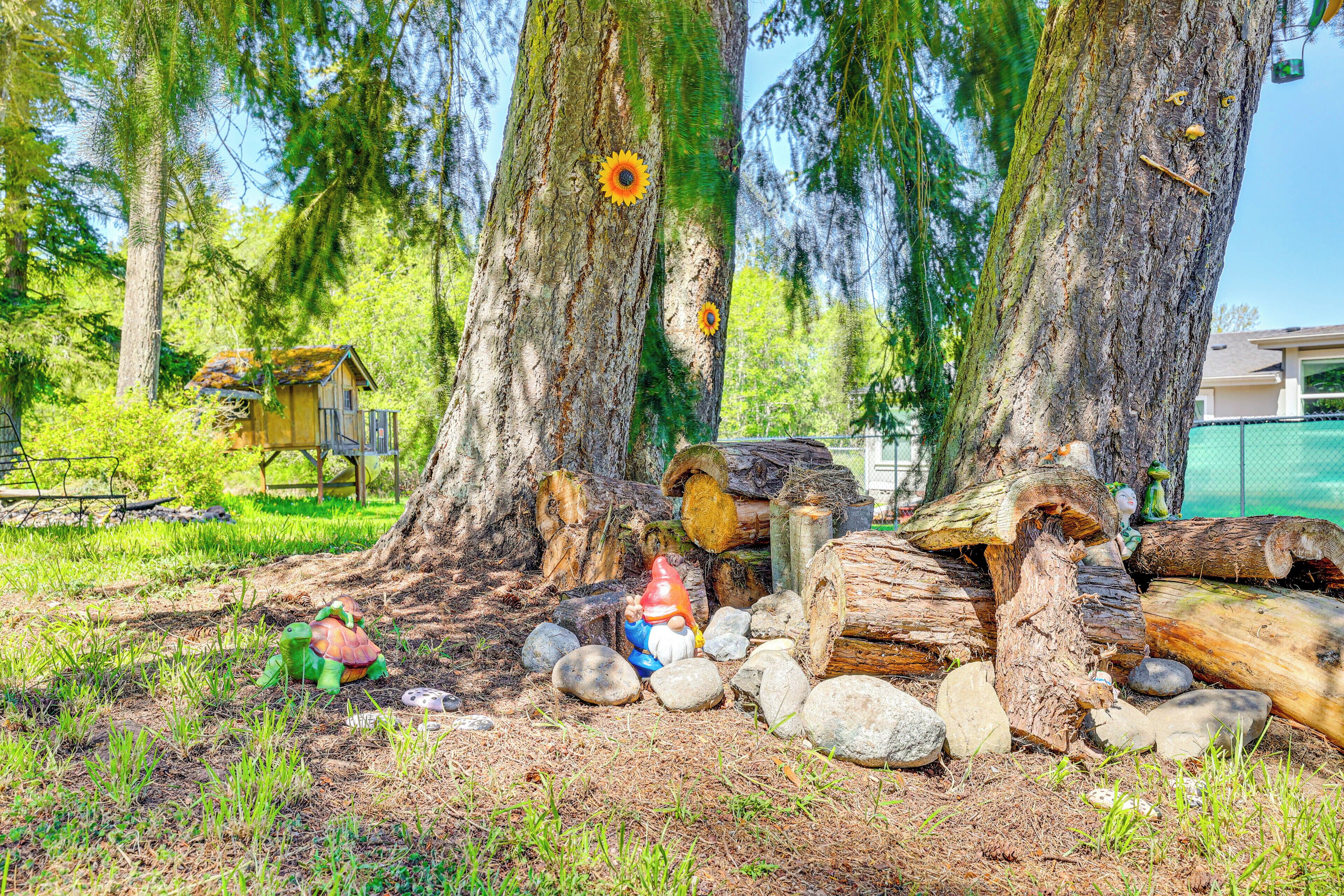 Un décor extérieur rustique, avec une structure en bois, une statue de gnome et un jouet en forme de tortue.