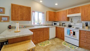 A kitchen with wooden cabinets, a white stove, a microwave, and a sink.
