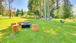 A grassy outdoor area with wooden benches and a fire pit.