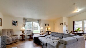 A living room with a sectional sofa, a recliner, and a dining area with a table and chairs.