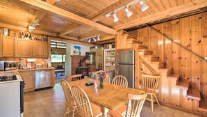 A wooden interior with a dining table, chairs, kitchen appliances, and a staircase. - Boothbay Harbor Cabin w/ Spacious Deck & Yard! (Boothbay Harbor)