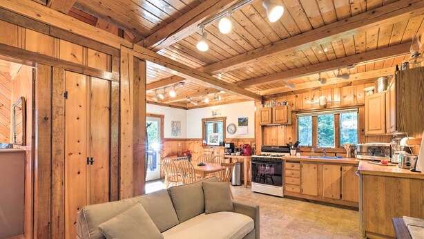 A cozy cabin interior with a wooden dining area, a kitchenette, and a sofa. - Boothbay Harbor Cabin w/ Spacious Deck & Yard! (Boothbay Harbor)