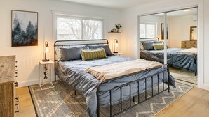 A bedroom with a bed, bedside tables, a mirror, and a window. - Hudson Valley Vacation Rental: Near Hiking (Beacon)