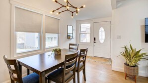 A dining area with a wooden table and chairs, a hanging light fixture, and a potted plant. - Hudson Valley Vacation Rental: Near Hiking (Beacon)