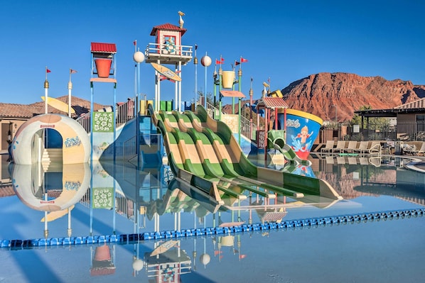 A water park with a large slide, a wave pool, and a mountain backdrop.