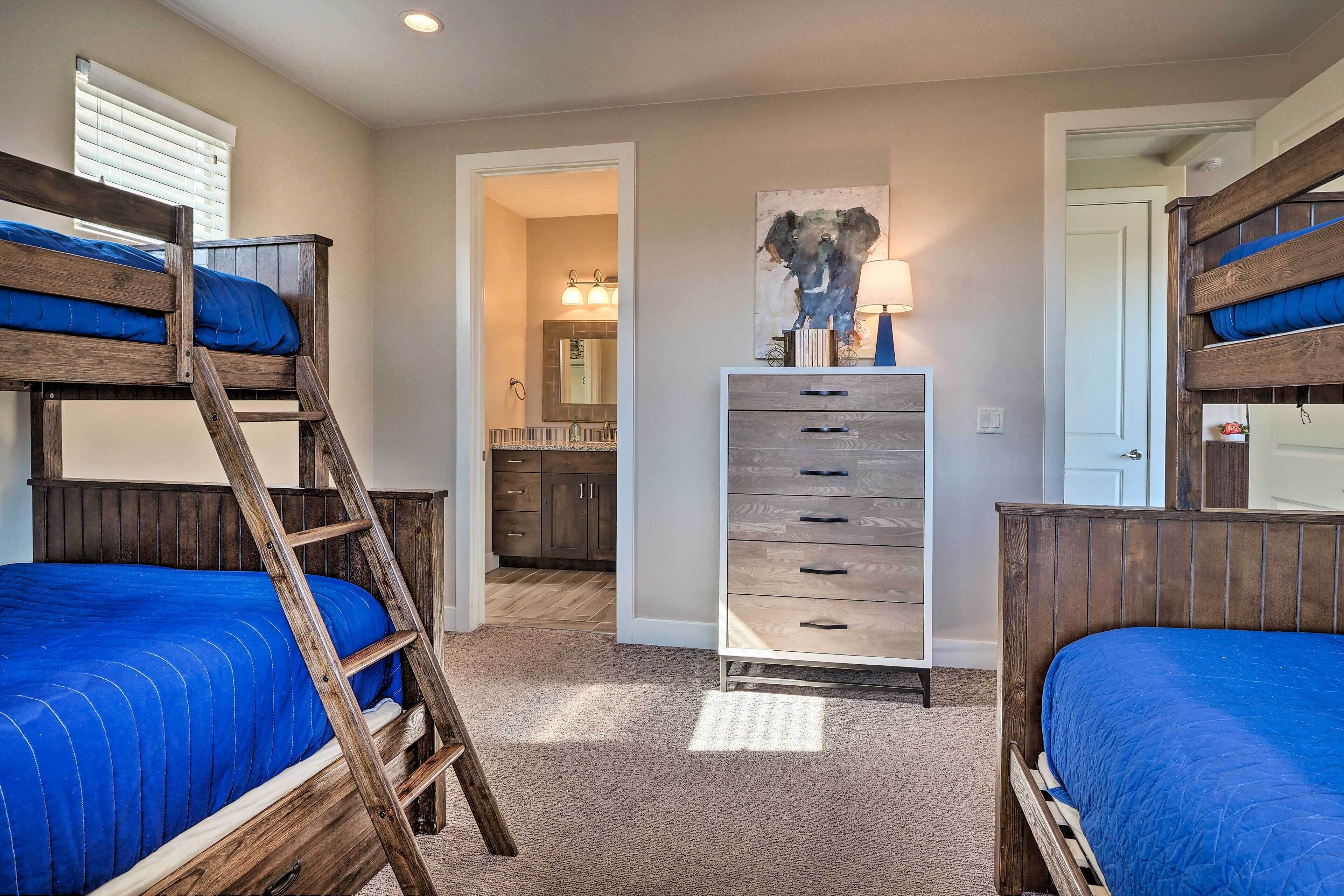 A bedroom with bunk beds, a dresser, and a bathroom visible through an open door.