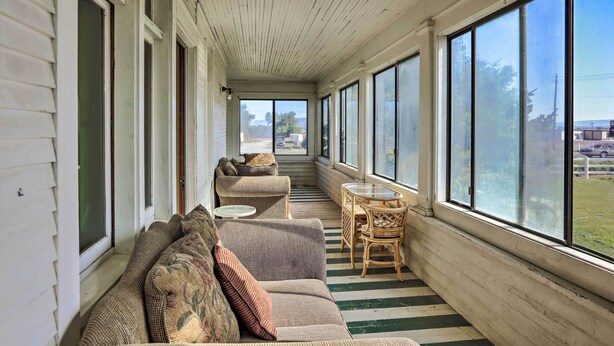 A covered porch with a striped floor, a sofa, a chair, and a small table. - Wyoming Farmhouse Retreat! 10 Mi to Bighorn Canyon (Lovell)