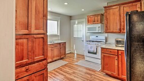 A kitchen with wooden cabinets, a refrigerator, a microwave, and an oven. - Wyoming Farmhouse Retreat! 10 Mi to Bighorn Canyon (Lovell)