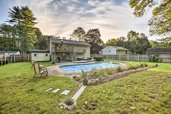 Un patio trasero con piscina, un porche cubierto y una casa de dos pisos.