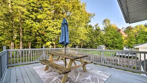 A wooden deck with a picnic table and umbrella, surrounded by a white fence and trees. - Updated Home w/ Pool + Deck ~ 2 Mi to Dtwn! (Saratoga Springs)