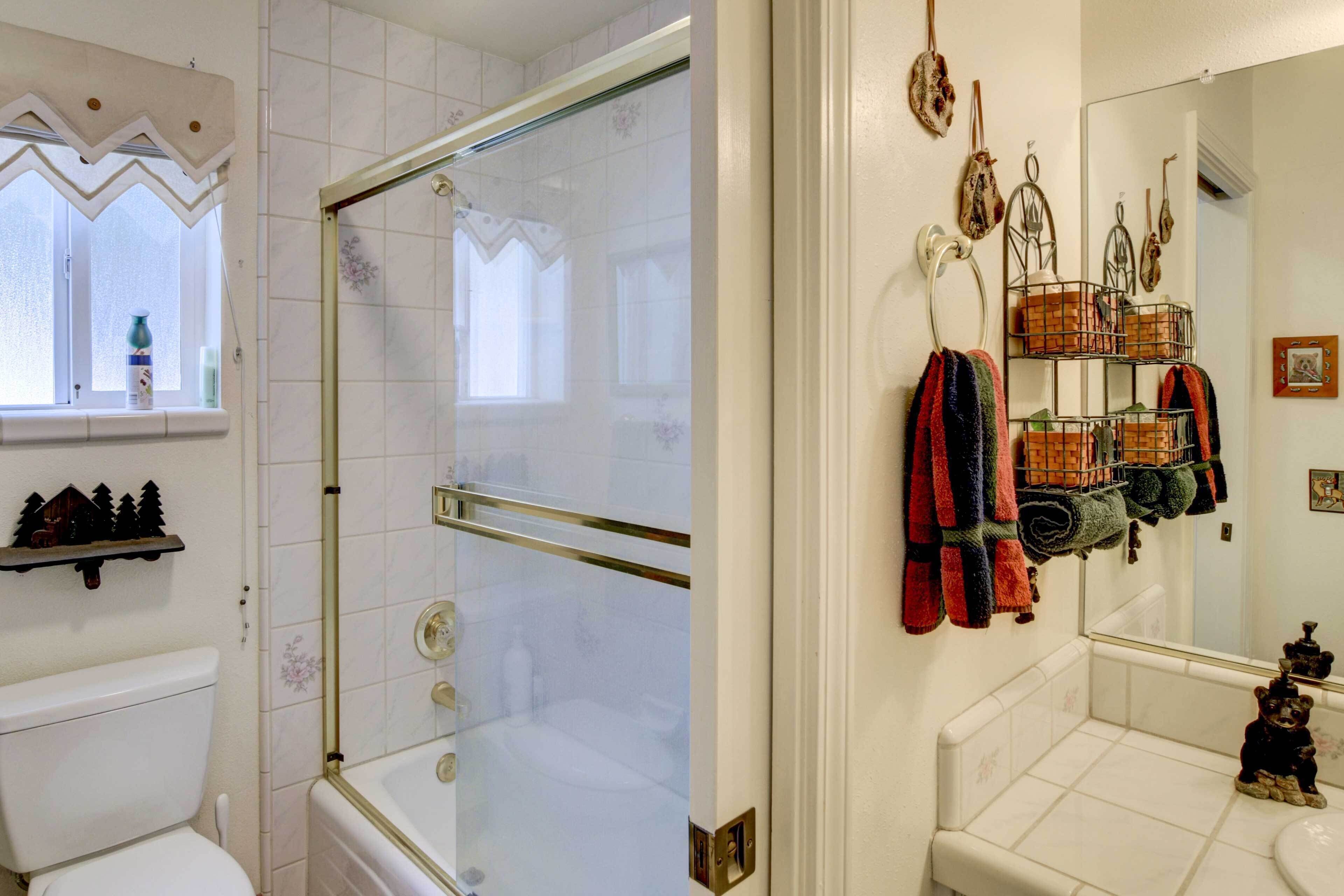 A bathroom with a glass shower enclosure, a toilet, a sink with a mirror, and a towel rack with towels.