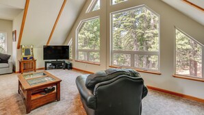 A cozy living room with a large window, a flat-screen TV, and a coffee table. - Pet-friendly California Cabin w/ Beach Access (Chester)