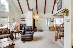 A spacious living room with a leather armchair, wooden beams on the ceiling, a fireplace, and a staircase leading to another level. - Pet-friendly California Cabin w/ Beach Access (Chester)