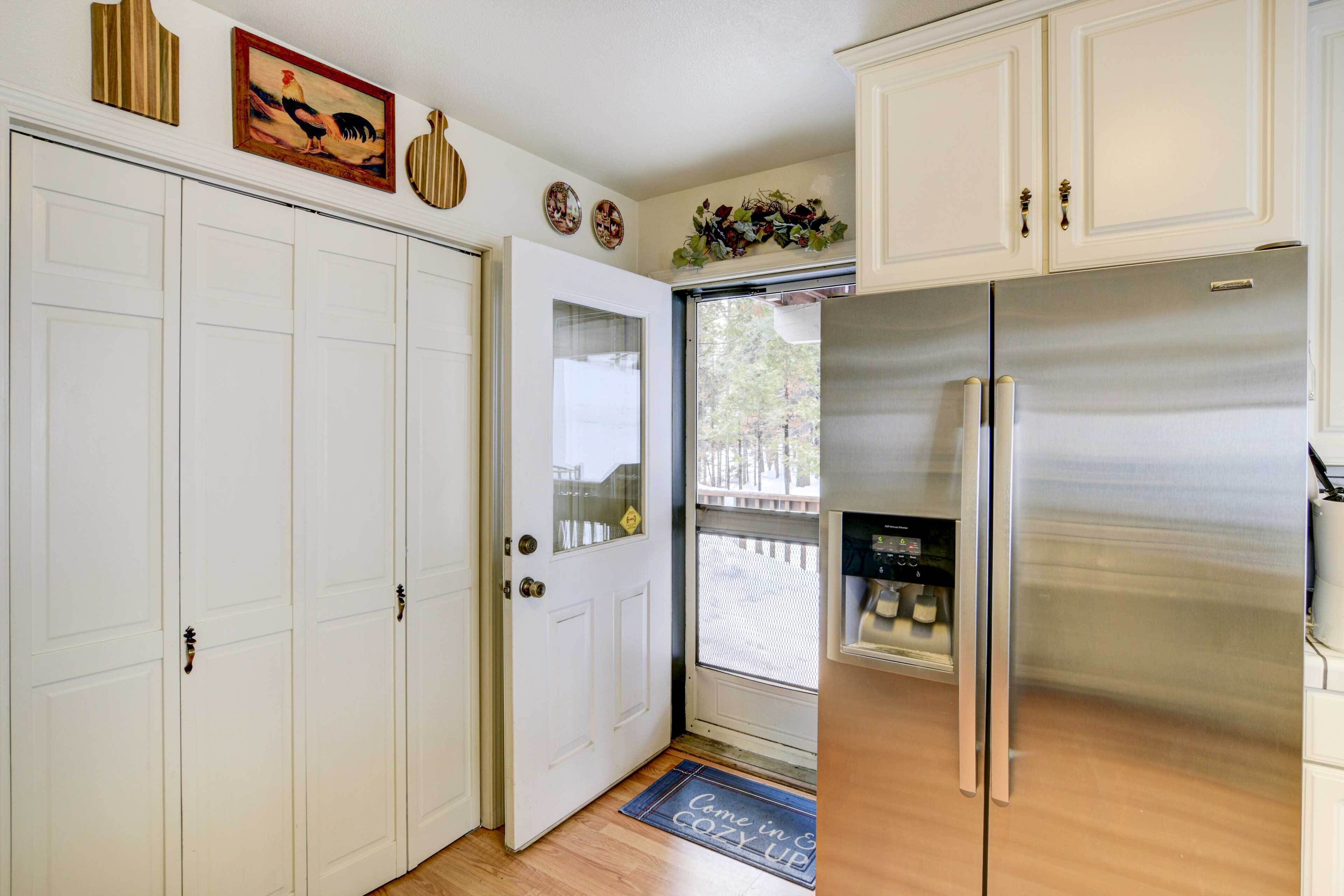 A kitchen with white cabinets, a stainless steel refrigerator, and a door with a glass panel.