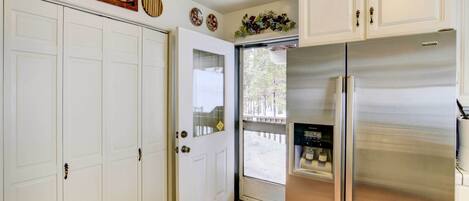 A kitchen with white cabinets, a stainless steel refrigerator, and a door with a glass panel.
