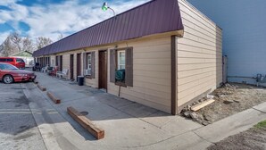 A row of single-story motel rooms with a brown exterior and a red roof.