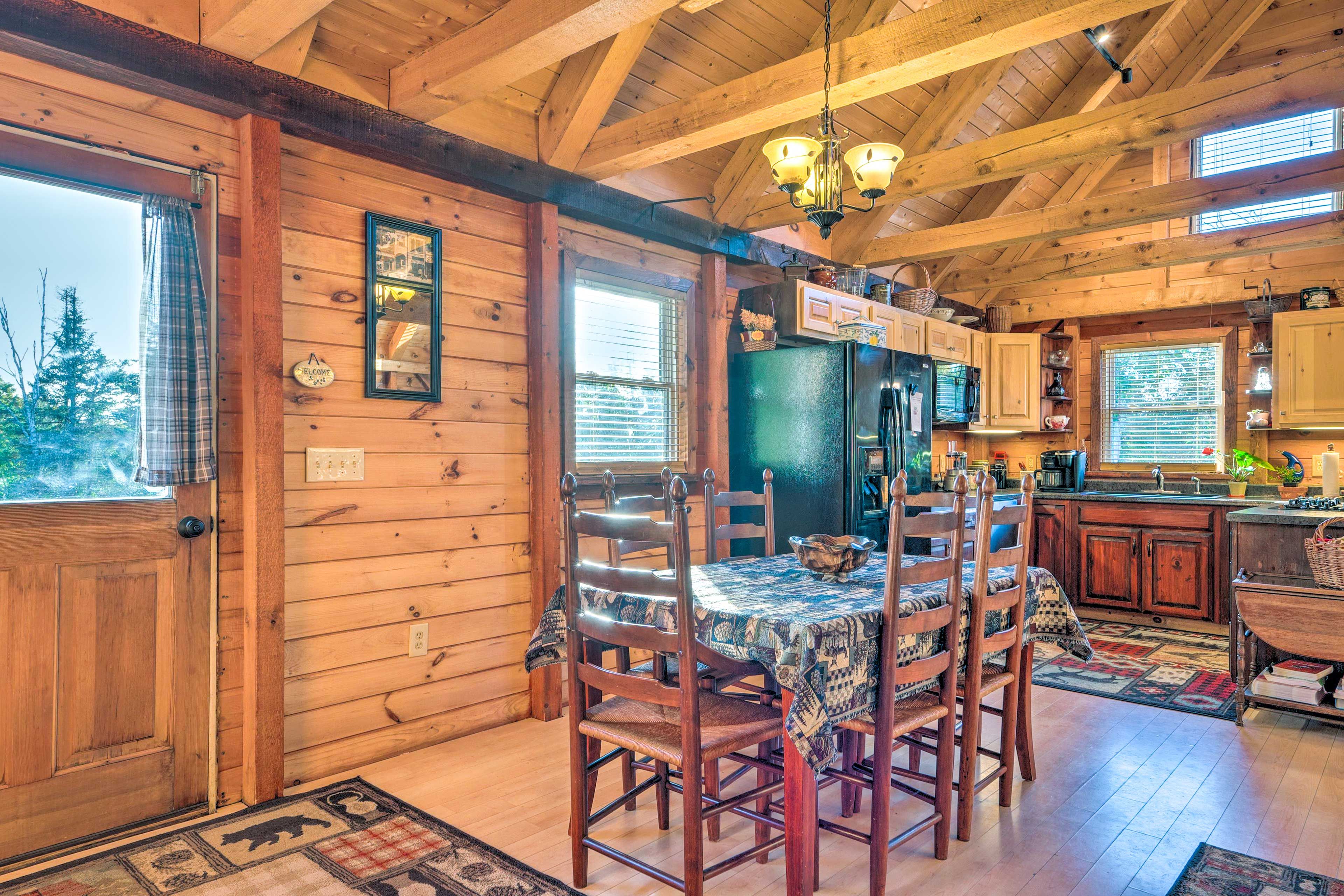 Un interior de madera con una mesa de comedor, sillas y una zona de cocina.