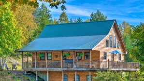 A wooden cabin with a green roof, a balcony with a railing, and a porch area with chairs. - West Danville Cabin: Day Trip to Stowe Mtn! (West Danville)