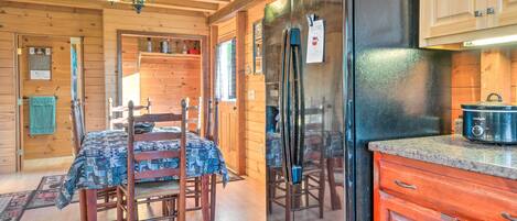 A wooden cabin interior with a dining area, a black refrigerator, and a red cabinet.