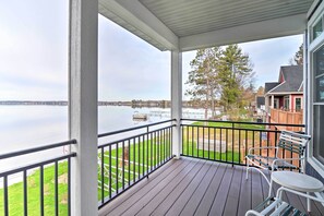 A covered outdoor area with a view of a lake, a wooden deck, and a seating area with a table and chairs. - Lakefront Home w/ Dock! 18 M to Caberfae Peaks (Cadillac)