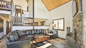 A spacious living room with a large sectional sofa, a wooden coffee table, and a stone fireplace. - Spacious Fairplay Cabin w/ Views ~ 21 Mi to Breck! (Alma)