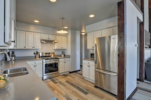 Una cocina moderna con armarios blancos, electrodomésticos de acero inoxidable y piso de madera.