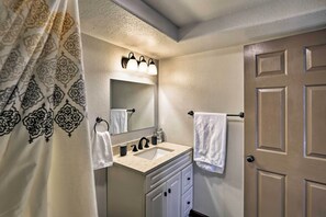 A bathroom with a sink, mirror, towel rack, and a door.
