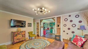 A living room with a large sofa, a patterned rug, and a television on the wall. - Colorful Bakersville Cottage: Views, Pets Allowed! (Bakersville)