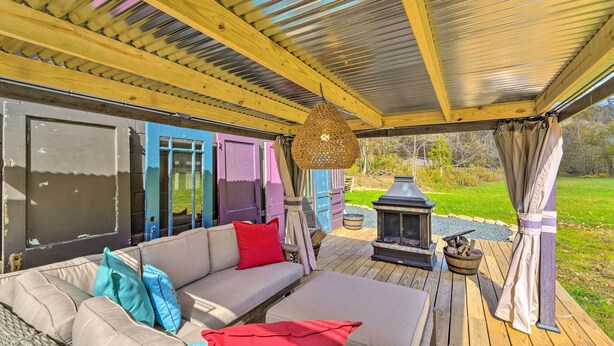 A covered outdoor seating area with a sofa, cushions, and a hanging light fixture. - Colorful Bakersville Cottage: Views, Pets Allowed! (Bakersville)