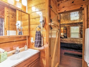 A wooden cabin bathroom with a sink, towel rack, and two hair dryers. - Deck & Hot Tub: Log Cabin Sevierville Studio! (Sevierville)