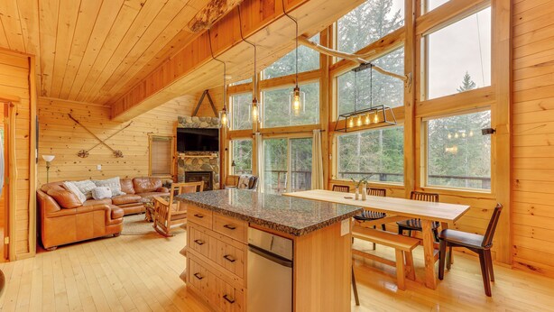 Interior de una cabaña de madera con cocina, comedor y sala de estar.