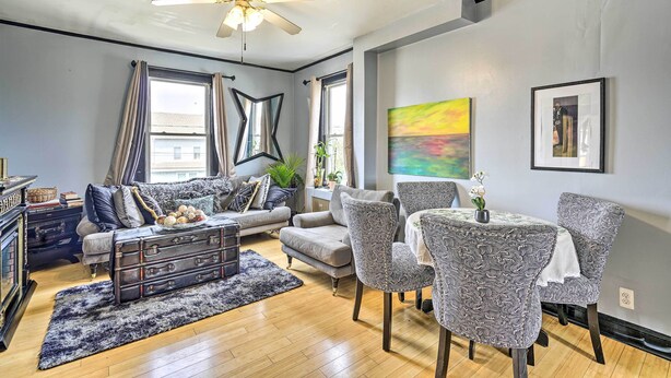 Una sala de estar moderna con sofá, sillones, una mesa de comedor y un ventilador de techo.