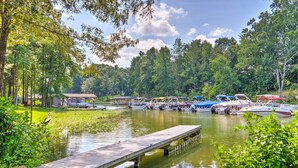 A lakeside dock with boats and a small building in the background.