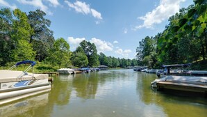 A calm river with boats docked along the banks, surrounded by lush greenery and trees.