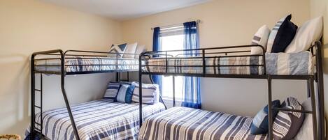 Un dormitorio con literas, una ventana con cortinas y una lámpara en el techo.